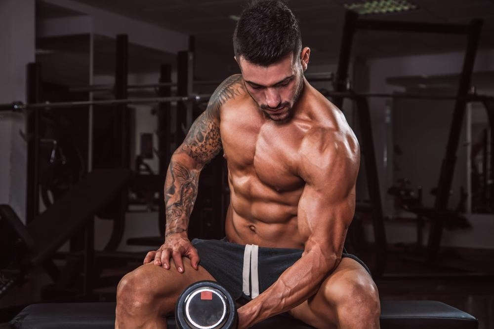 A good physique man doing concentration curl a bicep workout.