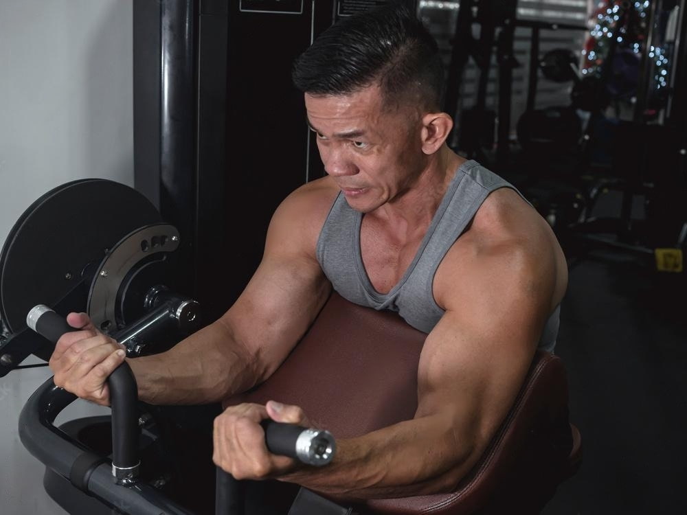 A guy with good physique doing preacher curls.