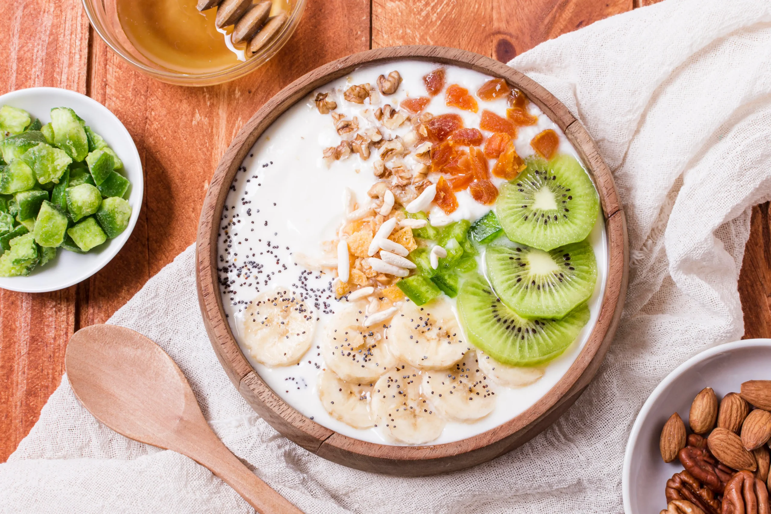 A delicious high-carb loaded bowl of Oat and yogurt adorned with banana slices, assorted nuts, and a sweet honey topping.